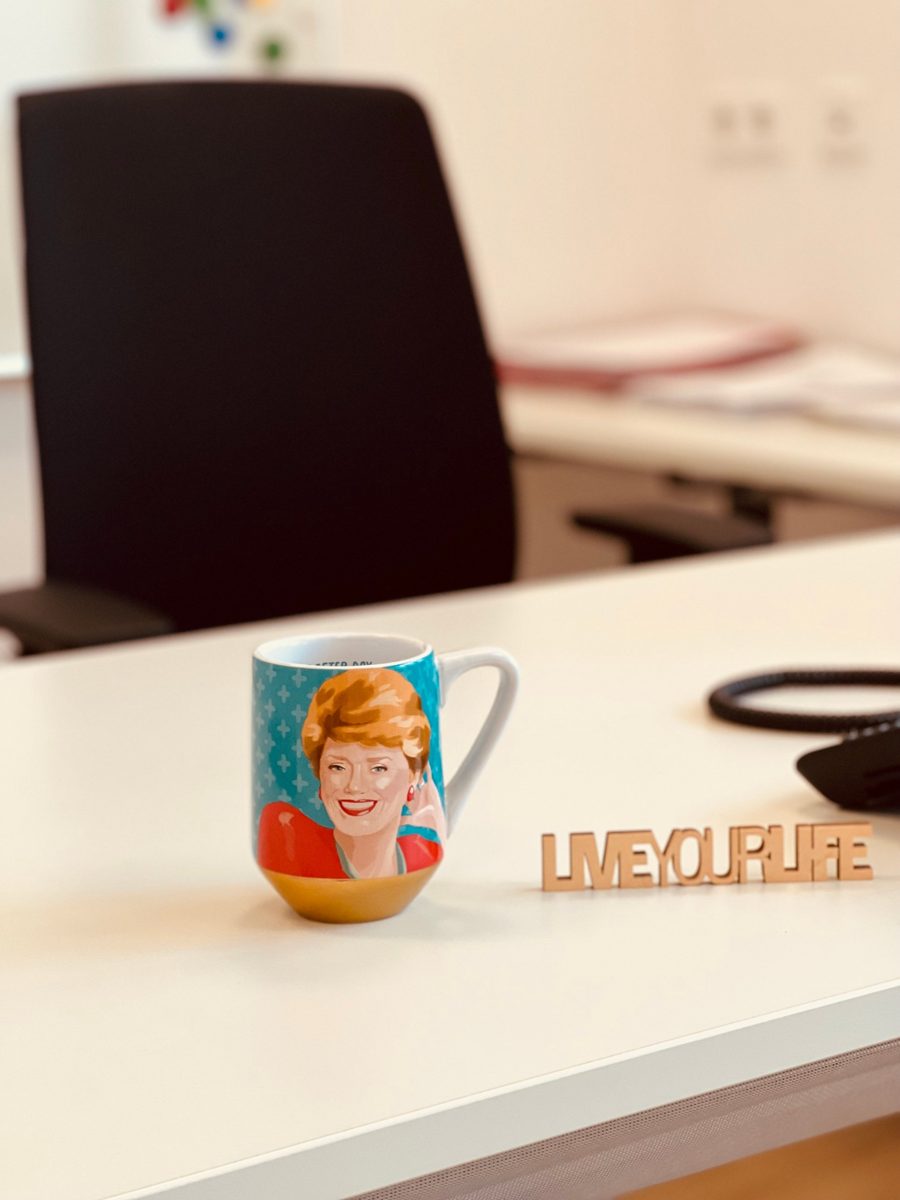 Tasse und Aufsteller mit der Aufschrift Live your life auf dem Schreibtisch